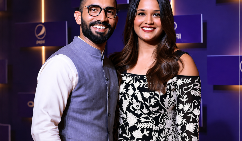Deepika Pallikal posing with her husband at a public event with a purple backdrop.
